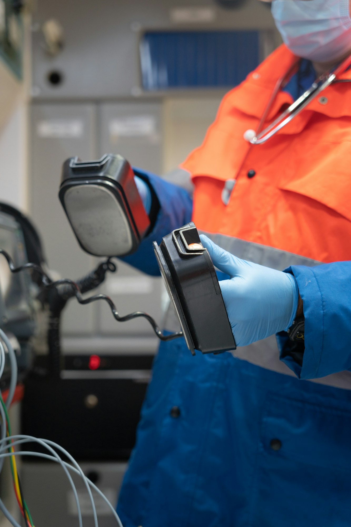photo of a medic holding the blades of a defibrillator in an ambulance